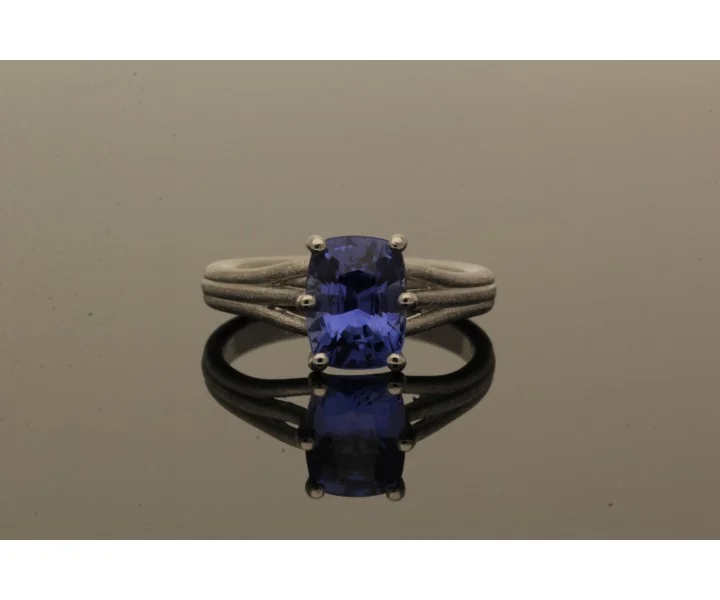 Platin-Ring mit blauem Saphir, Ansicht auf grauem Grund